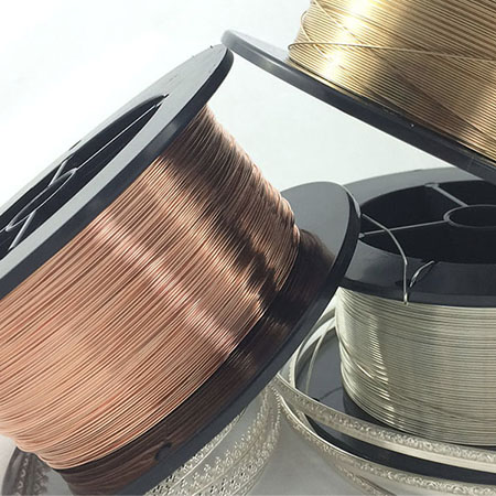 Spools of copper, gold, and silver wiring balancing on each other