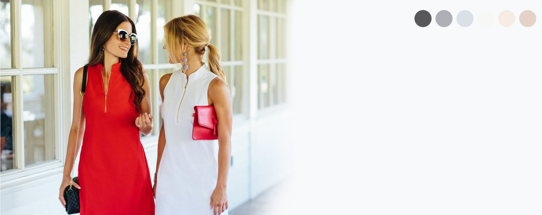 Woman in red dress smiling at woman in matching dress in white.